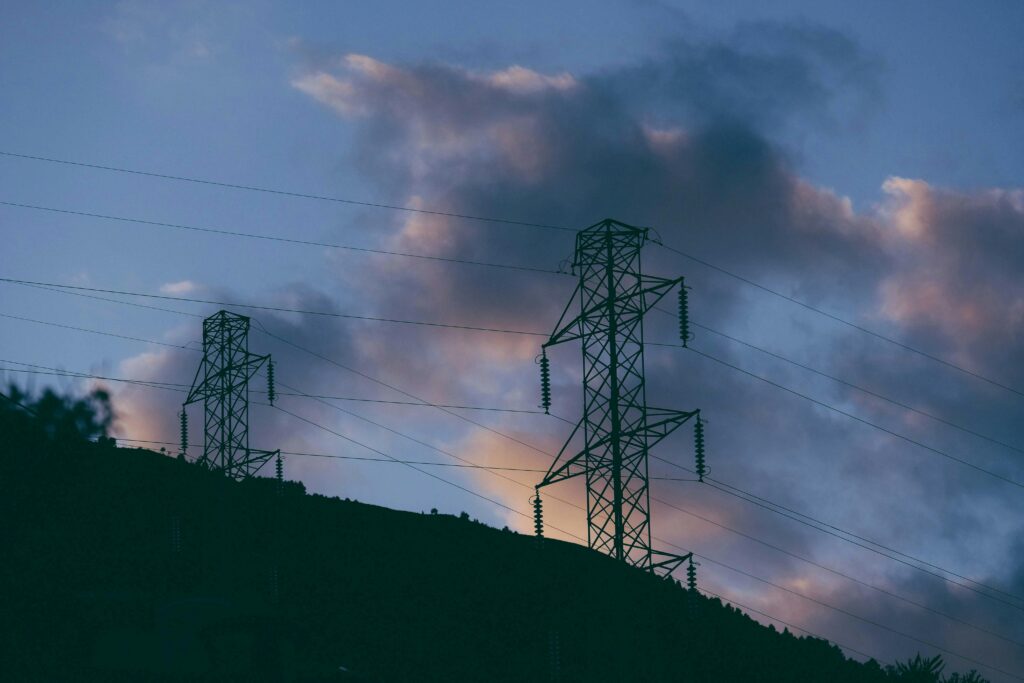 Silhouette of power pylons at sunset in Lombardia, Italy, capturing a dramatic industrial scene.